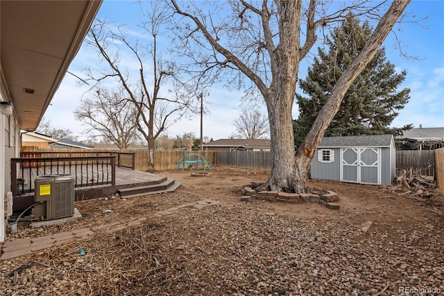 view of yard featuring a wooden deck, central AC, and a storage shed