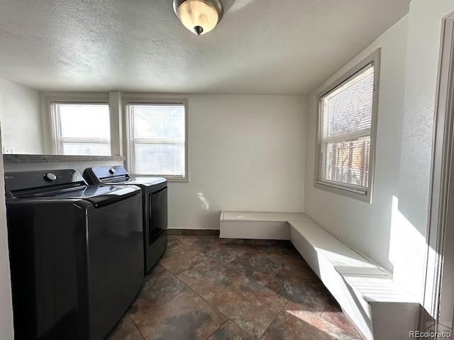 washroom with washer and clothes dryer, a healthy amount of sunlight, and a textured ceiling