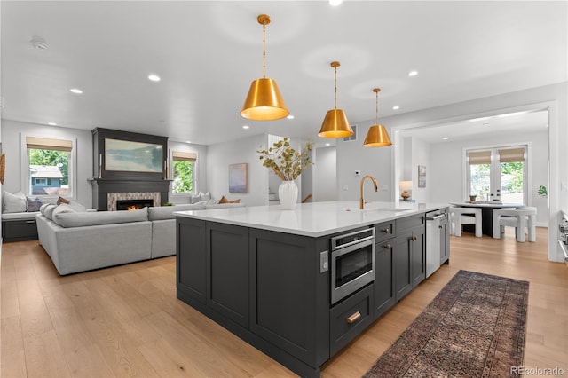 3256 S Corona, Englewood, CO 80113 - kitchen featuring a sink, stainless steel microwave, light countertops, light wood-style floors, and healthy amount of natural light