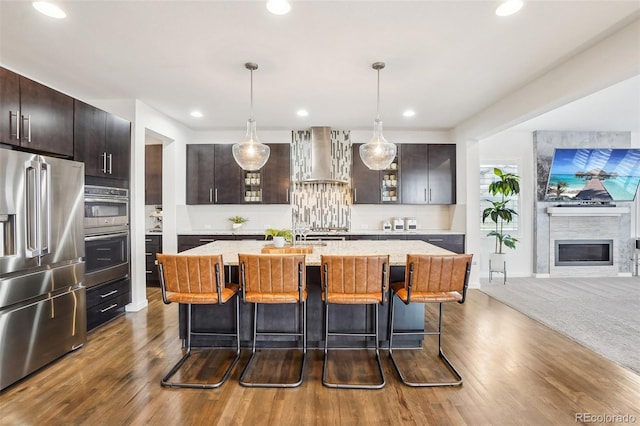 13960 Box Turtle Loop, Parker, CO 80134 - kitchen with wall chimney range hood, appliances with stainless steel finishes, dark wood-style floors, and a breakfast bar area