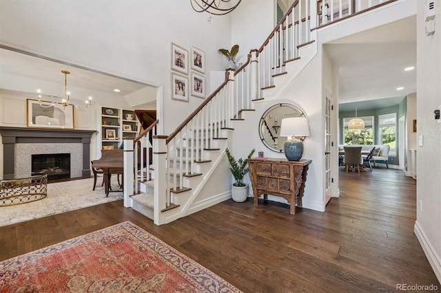 10660 Weathersfield Ct, Highlands Ranch, CO 80129 - staircase featuring a chandelier, wood finished floors, recessed lighting, a towering ceiling, and a fireplace