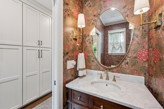 10660 Weathersfield Ct, Highlands Ranch, CO 80129 - bathroom featuring wallpapered walls, vanity, crown molding, and wood finished floors