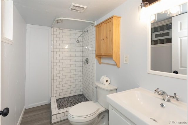 4595 S Lincoln St, Englewood, CO 80113 - bathroom featuring toilet, tiled shower, wood finished floors, and visible vents