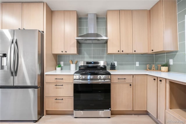 kitchen with backsplash, light brown cabinets, wall chimney range hood, and appliances with stainless steel finishes