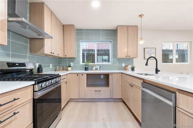 kitchen featuring plenty of natural light, light brown cabinets, stainless steel appliances, and wall chimney range hood