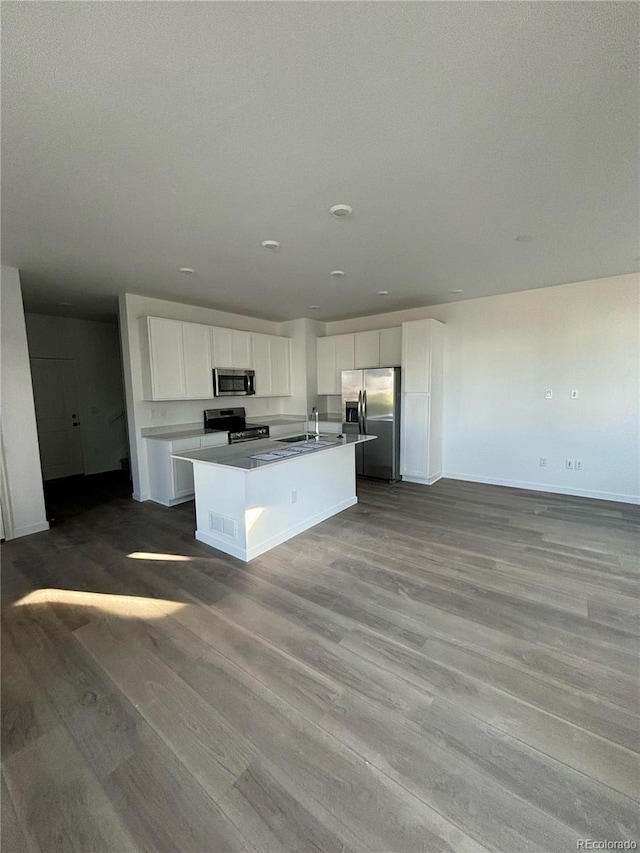 kitchen featuring white cabinets, sink, light wood-type flooring, an island with sink, and stainless steel appliances