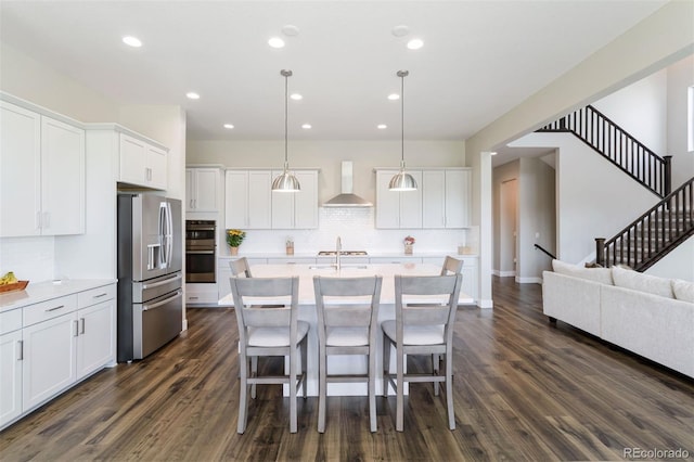 kitchen featuring white cabinetry, pendant lighting, wall chimney range hood, and appliances with stainless steel finishes