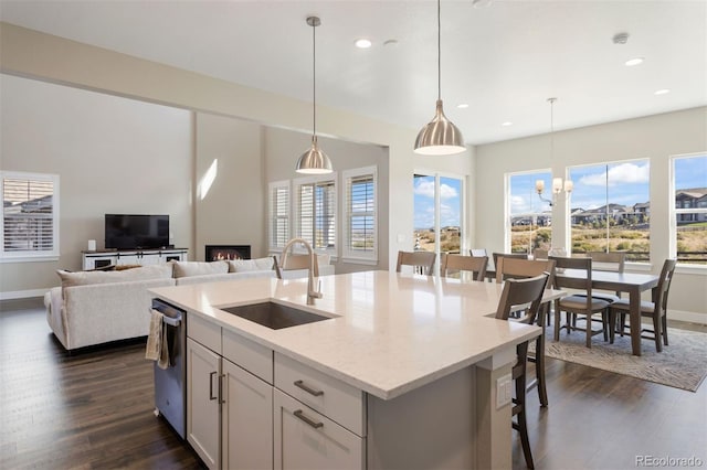 kitchen with decorative light fixtures, a center island with sink, a breakfast bar area, and sink