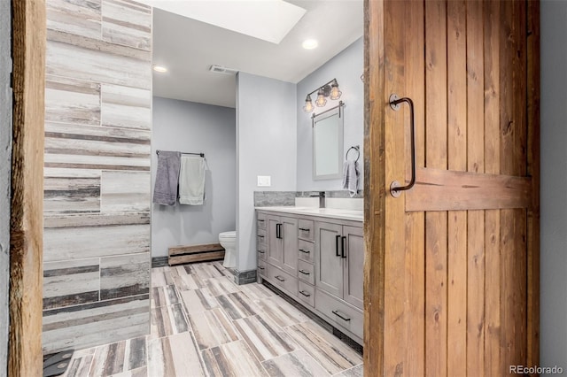 1341 Tomichi Dr, Franktown, CO 80116 - bathroom featuring a skylight, toilet, vanity, and recessed lighting