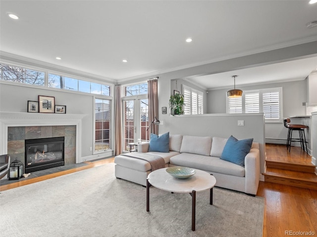 living area with crown molding, a tiled fireplace, wood finished floors, and recessed lighting