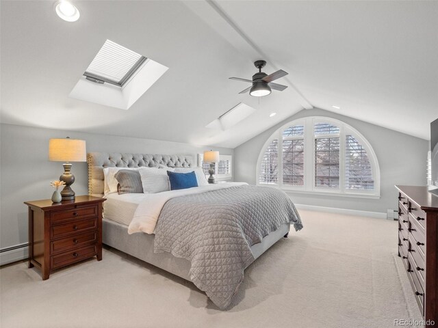 bedroom with ceiling fan, vaulted ceiling with skylight, light colored carpet, a baseboard heating unit, and baseboards