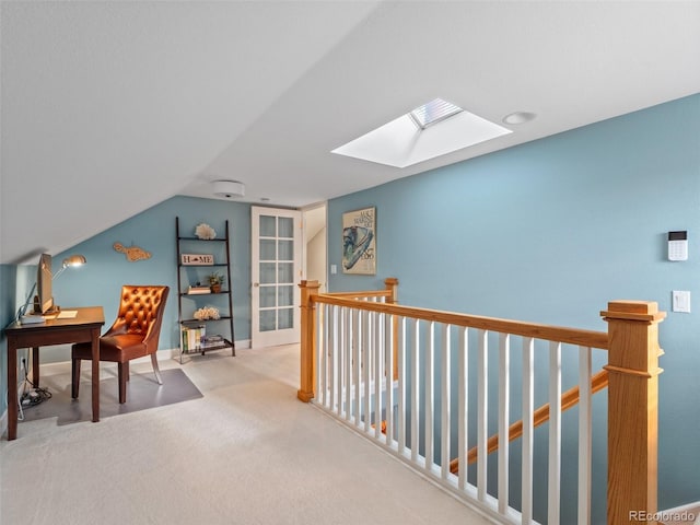 carpeted office space with vaulted ceiling with skylight