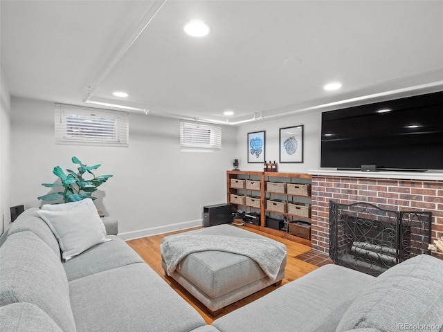 living room featuring baseboards, a brick fireplace, wood finished floors, and recessed lighting