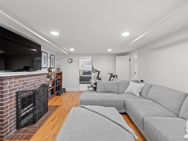 living area with baseboards, a brick fireplace, wood finished floors, and recessed lighting