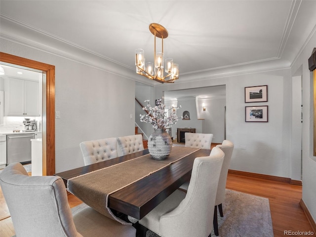 dining space with crown molding, an inviting chandelier, light wood-type flooring, baseboards, and stairs