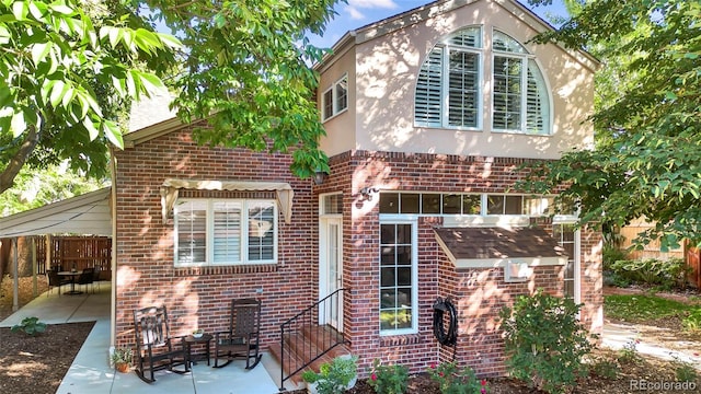 back of property featuring stucco siding, brick siding, fence, and a patio