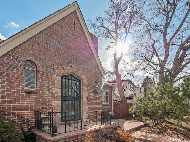 view of home's exterior with brick siding and fence