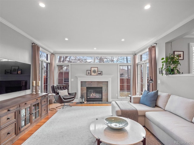 living room featuring light wood-style flooring, a fireplace, recessed lighting, and ornamental molding