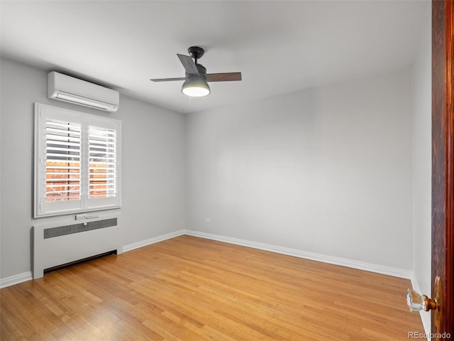 unfurnished room with an AC wall unit, light wood-type flooring, ceiling fan, radiator, and baseboards