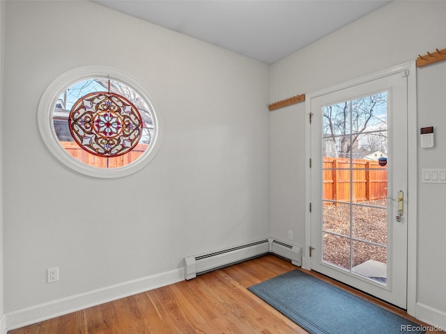 doorway with a baseboard heating unit, baseboards, light wood finished floors, and plenty of natural light
