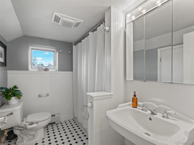 full bath featuring a sink, wainscoting, toilet, lofted ceiling, and visible vents