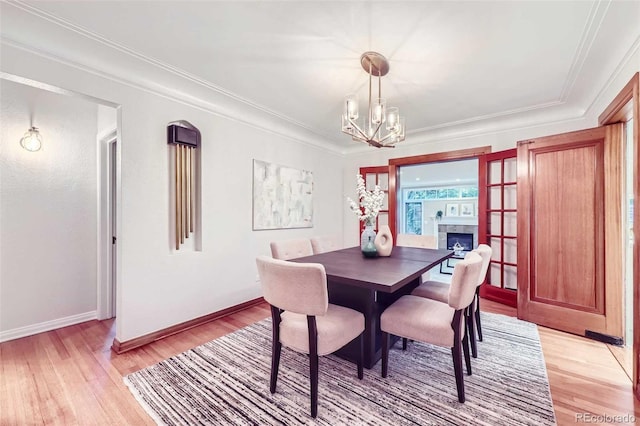 926 S Fillmore Way, Denver, CO 80209 - dining space featuring light wood finished floors, a chandelier, baseboards, ornamental molding, and a fireplace