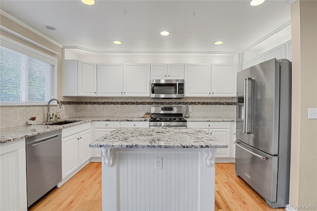 9665 Whitecliff Pl, Highlands Ranch, CO 80129 - kitchen with appliances with stainless steel finishes, a sink, a kitchen island, light wood finished floors, and recessed lighting