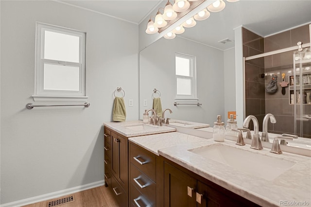 9665 Whitecliff Pl, Highlands Ranch, CO 80129 - bathroom with double vanity, crown molding, a stall shower, baseboards, and wood finished floors