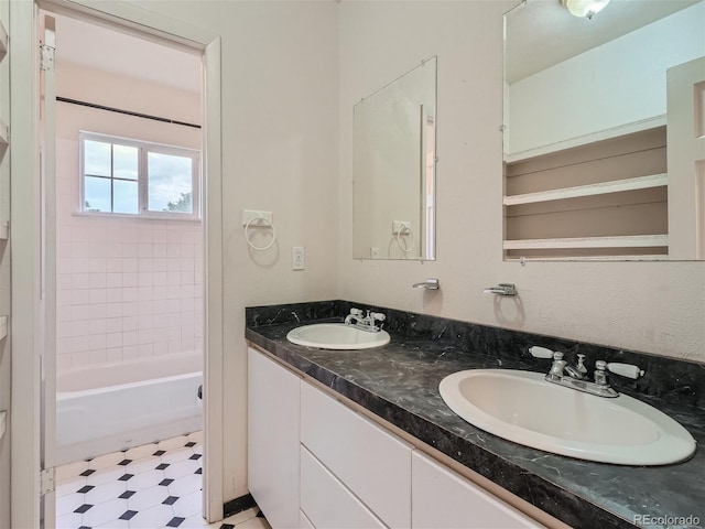 bathroom featuring vanity with extensive cabinet space, dual sinks, tile flooring, and tiled shower / bath