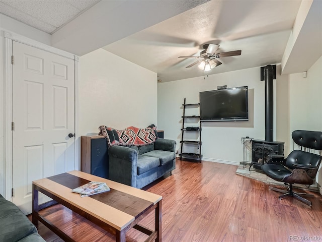 living room featuring hardwood / wood-style flooring, ceiling fan, and a wood stove