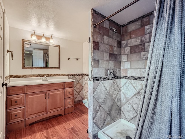 bathroom featuring tile walls, a shower with curtain, hardwood / wood-style floors, vanity, and a textured ceiling