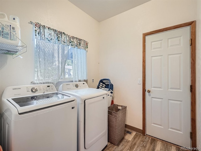 laundry area with independent washer and dryer and light wood-type flooring