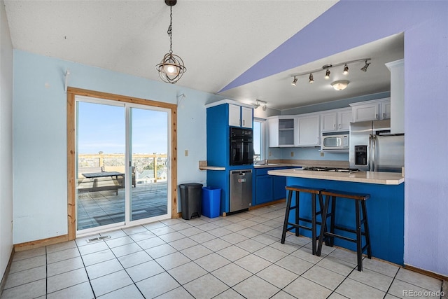 kitchen featuring a kitchen breakfast bar, blue cabinets, decorative light fixtures, white cabinets, and appliances with stainless steel finishes