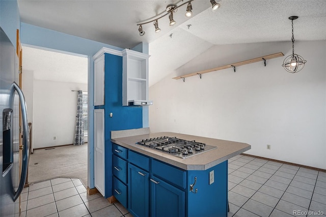 kitchen featuring stainless steel appliances, vaulted ceiling, blue cabinets, light colored carpet, and hanging light fixtures