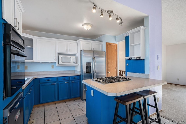 kitchen with a kitchen bar, appliances with stainless steel finishes, white cabinetry, and blue cabinets