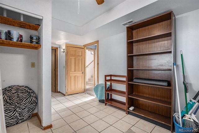 interior space with light tile patterned floors, connected bathroom, and ceiling fan