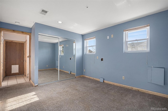 unfurnished bedroom with carpet, a closet, and multiple windows