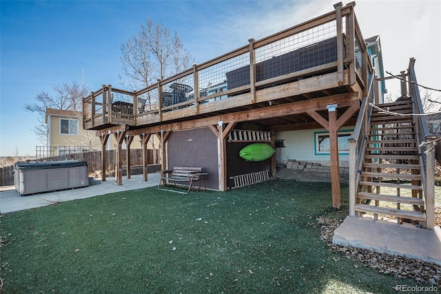 back of property featuring a lawn, a wooden deck, a patio, and a hot tub