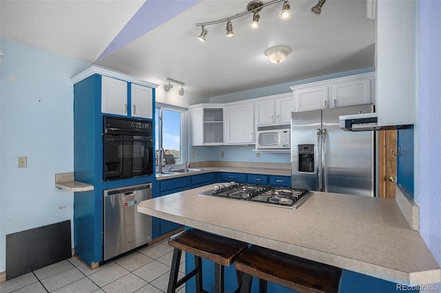 kitchen with white cabinets, a kitchen bar, stainless steel appliances, and sink