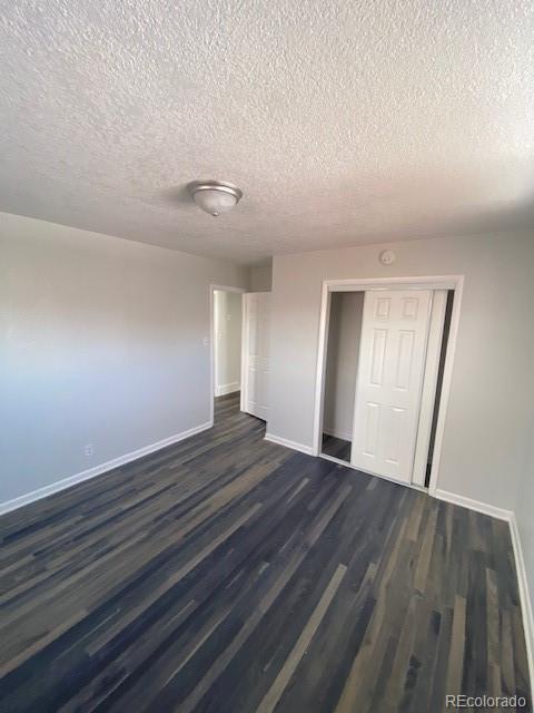 unfurnished bedroom with dark wood-type flooring, a closet, and a textured ceiling