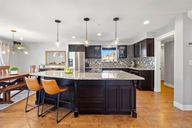 kitchen with a center island, pendant lighting, and stainless steel refrigerator with ice dispenser