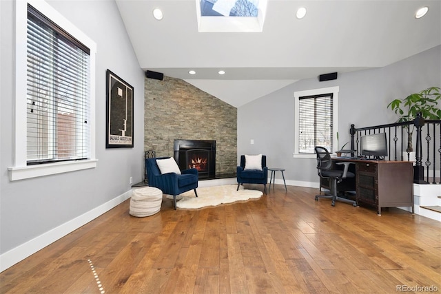 living area featuring light wood-style flooring, recessed lighting, a fireplace, baseboards, and lofted ceiling with skylight