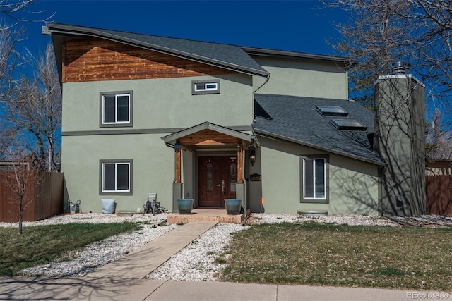 view of front of property with roof with shingles, fence, a front lawn, and stucco siding