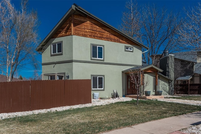 view of property exterior featuring a yard, fence, and stucco siding