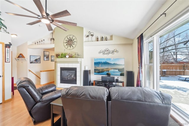 living room with a fireplace, hardwood / wood-style flooring, vaulted ceiling, and ceiling fan