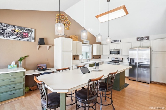 dining room featuring high vaulted ceiling, sink, and light hardwood / wood-style floors