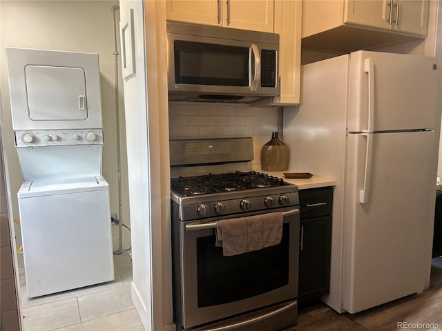 kitchen featuring white cabinetry, decorative backsplash, stainless steel appliances, and stacked washer and clothes dryer