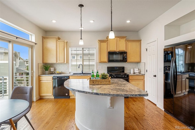 kitchen with light brown cabinetry, tasteful backsplash, black appliances, and light hardwood / wood-style floors