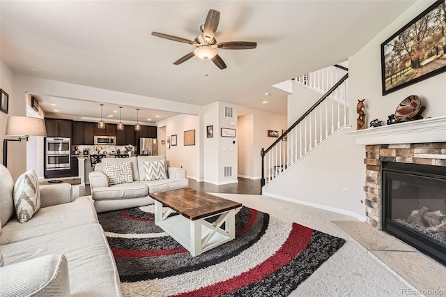 25128 E Maple Ave, Aurora, CO 80018 - living area featuring a ceiling fan, stairway, light carpet, a stone fireplace, and baseboards