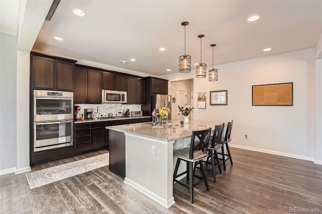 25128 E Maple Ave, Aurora, CO 80018 - kitchen featuring appliances with stainless steel finishes, an island with sink, dark wood-type flooring, dark brown cabinetry, and recessed lighting
